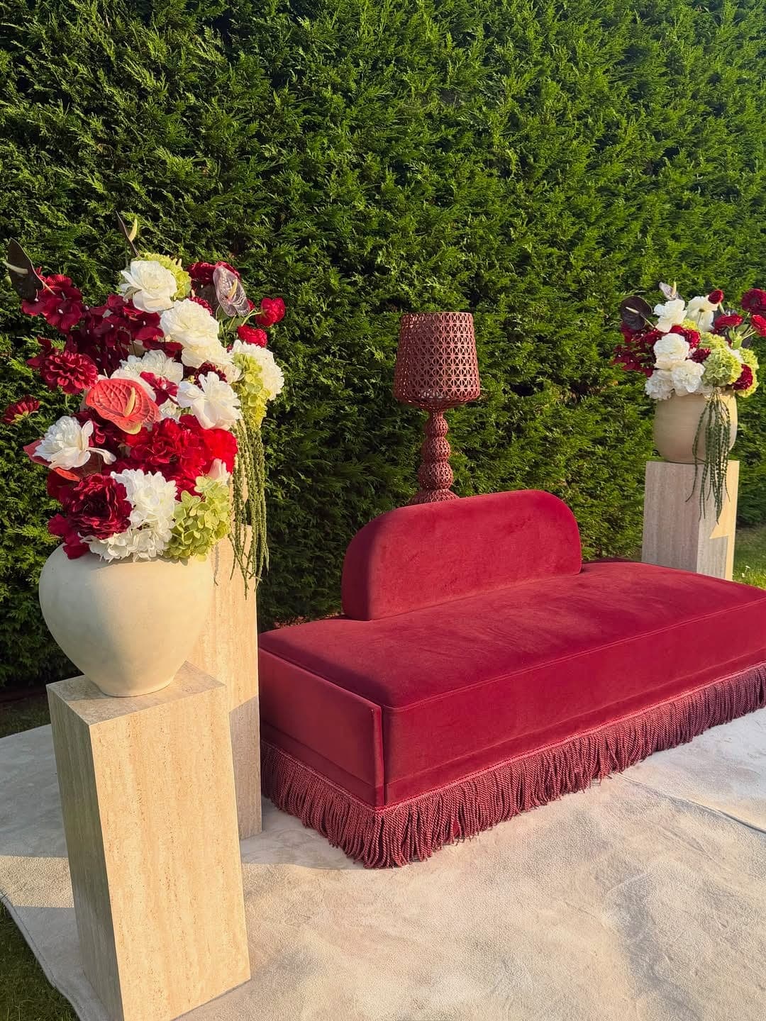 Trône mariée Siem Events — daybed en velours, franges de passementerie, socle habillé, composition florale sur travertin